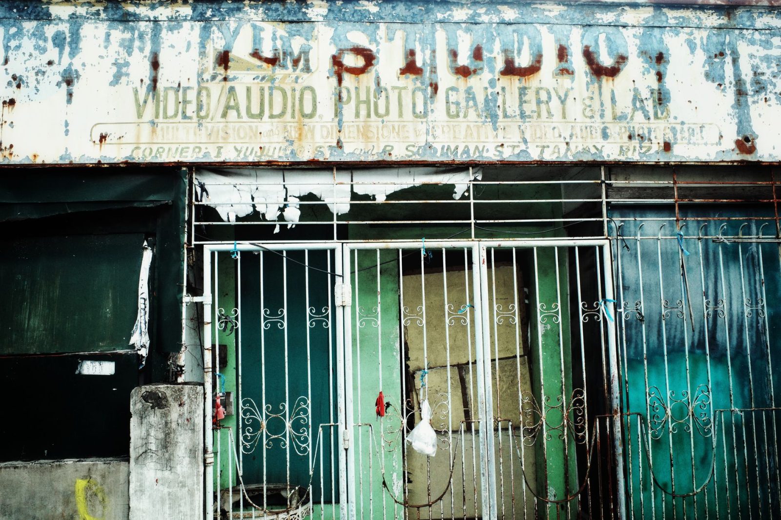 The worn facade of an old studio with peeling paint and rusted signs