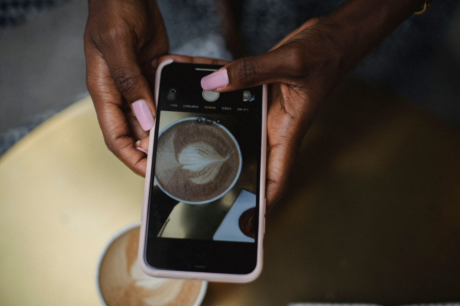 Someone photographing a latte with a smartphone