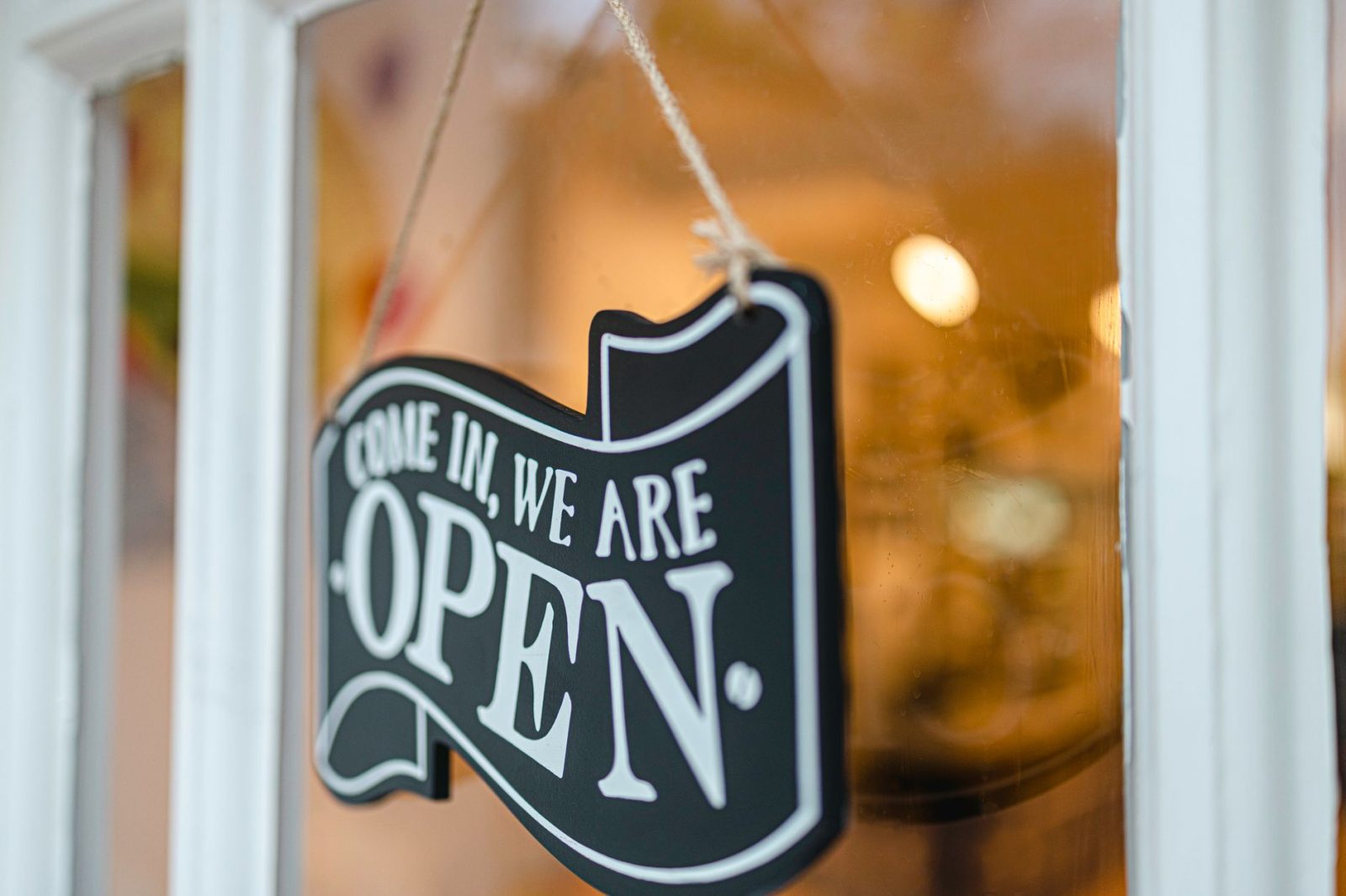 An open sign hanging on a glass shop door