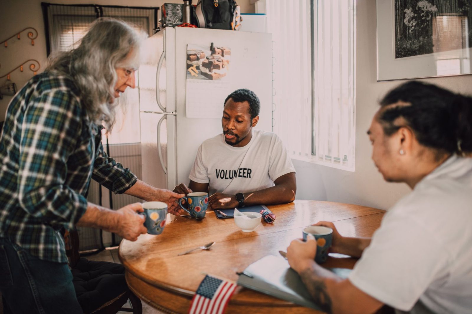 Three volunteers sharing coffee and ideas around a kitchen table