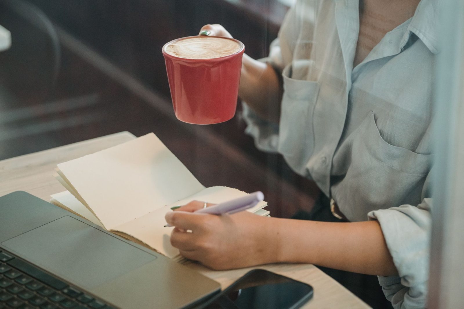 A woman writing in a notebook in a café
