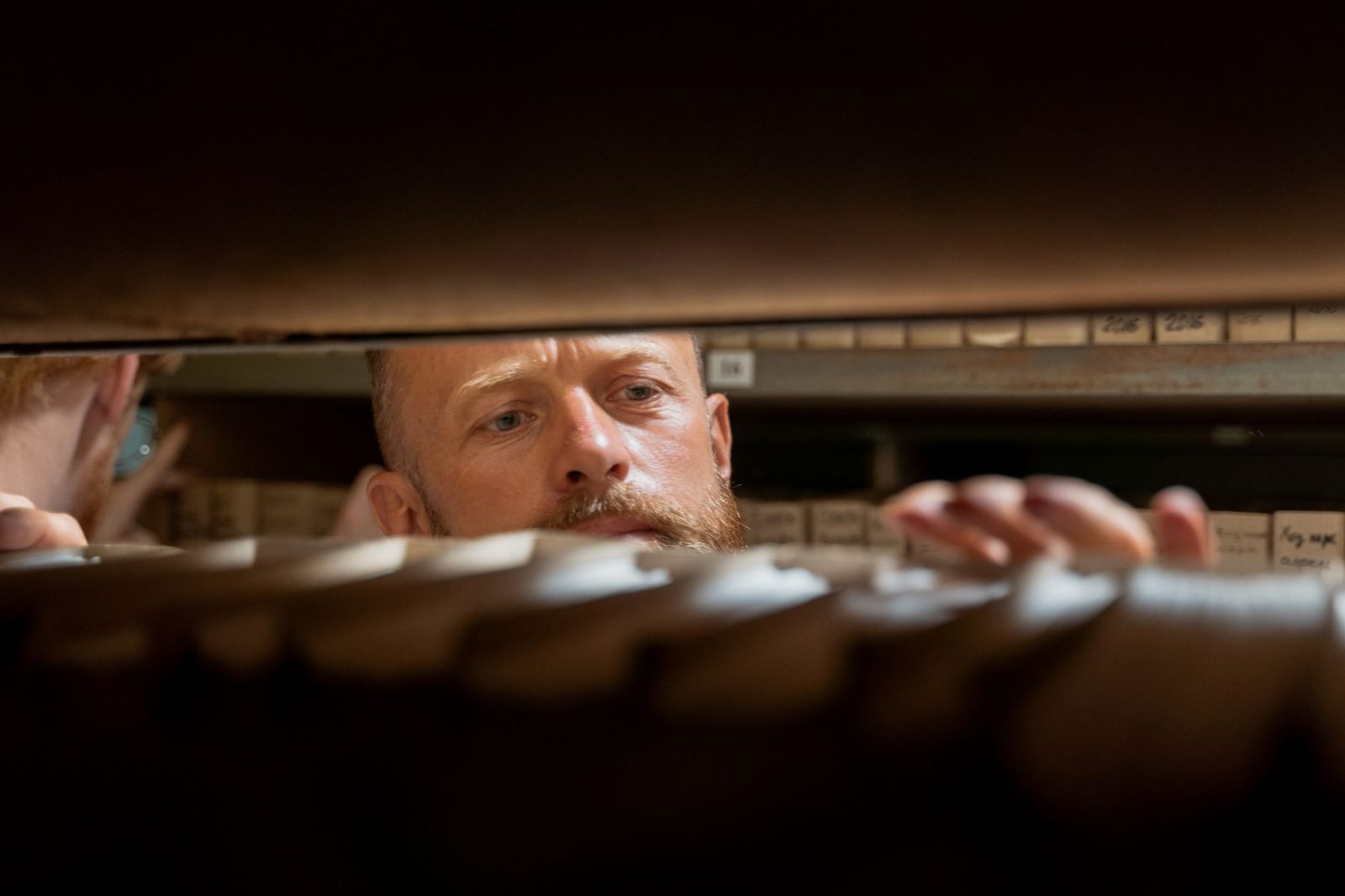 A man searching through folders in an office storage room